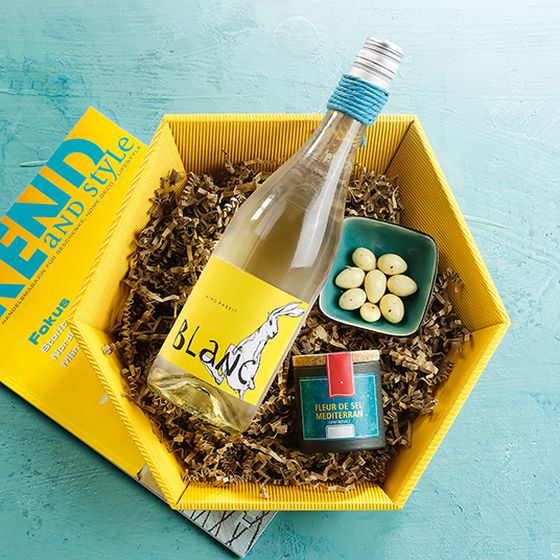 Panier-cadeau hexagonal vague ouverte en jaune avec du vin blanc.