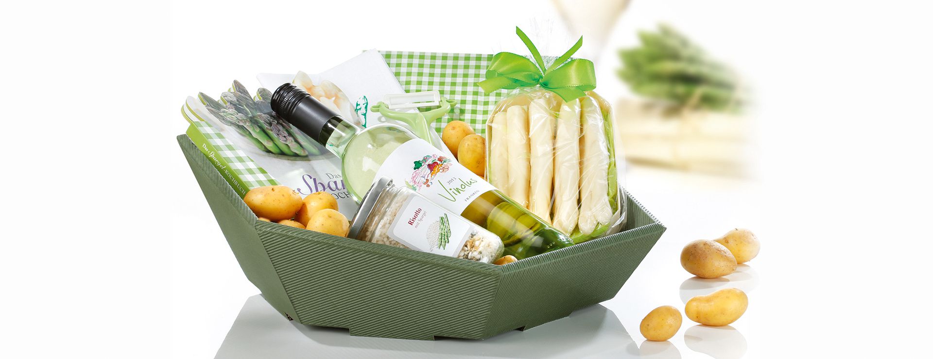 Zeshoekige geschenkmand van open golfkarton en schuine voorkant met witte wijn en asperges.